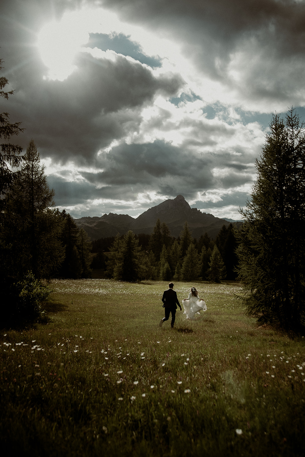 Dolomites elopement photographer - a couple running in the Dolomites meadows