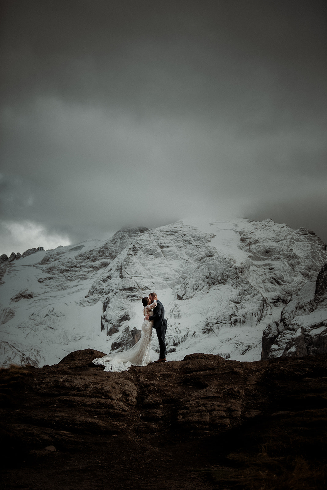 Custom Dolomites Elopement Packages - couple kissing in front of dramatic snowy mountain in the background